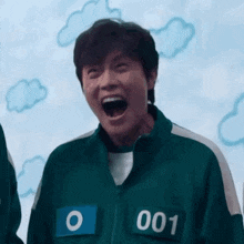 a man in a squid game uniform is laughing with his mouth wide open .