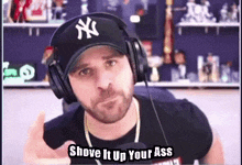 a man wearing headphones and a ny hat with the words shove it up your ass below him