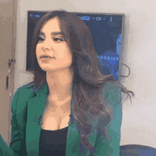 a woman in a green jacket is standing in front of a tv that says ' netflix ' on it