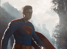 a man in a superman costume stands in front of a city