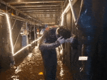 a man is standing in a flooded hallway with the word lutts on the bottom right