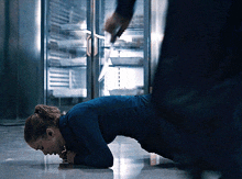 a woman in a blue shirt is crawling on the floor