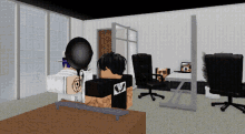 a man in a black shirt with the letter v on the back sits at a desk