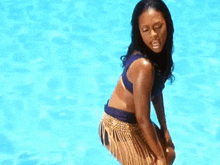 a woman in a bikini is kneeling in a pool .