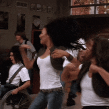 a group of people are dancing in a room with a man in a wheelchair in the background