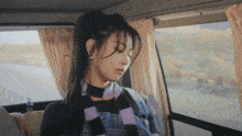 a woman in a plaid scarf looks out the window