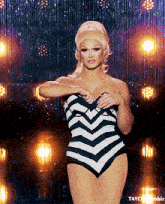 a woman in a black and white striped swimsuit is standing in front of a curtain that says t4yc on it