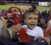 a young boy is holding a red object in front of a scoreboard that says ' or ' on it