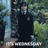a girl in a school uniform with the words it 's wednesday above her