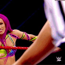 a woman with purple hair is in a wrestling ring with a w logo