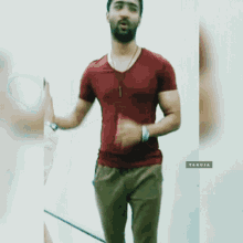 a man in a red shirt is standing with his hands folded in prayer
