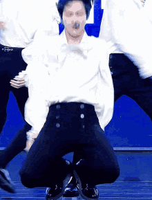 a man in a white shirt and black pants is kneeling down on a stage