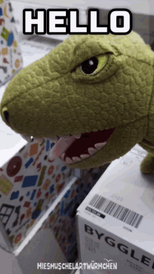 a stuffed dinosaur is sitting on a box that says byggle