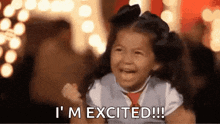 a little girl is holding her fist in the air and saying `` i 'm excited ! ''