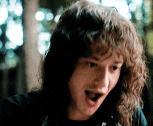 a man with long curly hair is making a funny face with his mouth open
