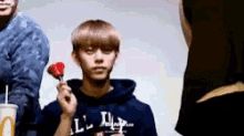 a young man is holding a red rose on a stick in his hand .