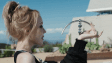 a woman in a black top is holding a metal object in her hand .