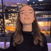 a woman wearing a black sweater is making a funny face with her eyes closed