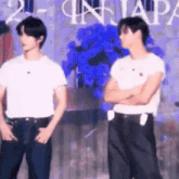 two men are standing next to each other with their arms crossed in front of a stage .