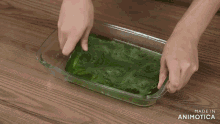 a person is putting green liquid in a glass container that says made in animotica on the bottom