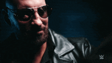 a man wearing sunglasses and a leather jacket has a w logo on the bottom right