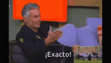 a man sitting in a chair applauding with the words exacto below him