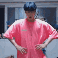 a man with blue hair is wearing a pink shirt .