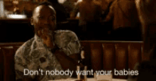 a man is sitting at a table with a bottle of beer and says " don 't nobody want your babies "