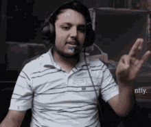 a man wearing headphones and a striped shirt is giving the peace sign
