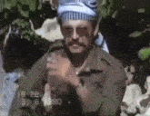 a man with a mustache and sunglasses is wearing a bandana and holding a gun .