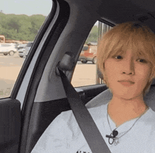 a man with blonde hair is sitting in a car with a black seat belt