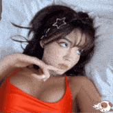 a woman in a red top with a star in her hair is laying on a bed