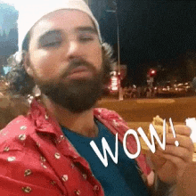 a man with a beard is holding a piece of food and says wow .