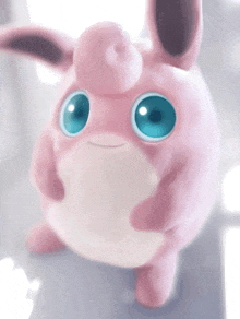 a pink stuffed animal with blue eyes is looking up at the camera