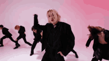 a group of young men are dancing in front of a red background