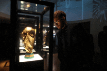 a man wearing glasses looks at a trophy in a case