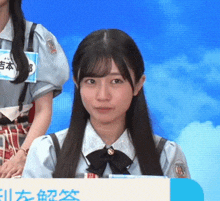 a girl sitting in front of a sign with chinese writing