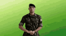a man in a military uniform and beret is standing with his hands folded .