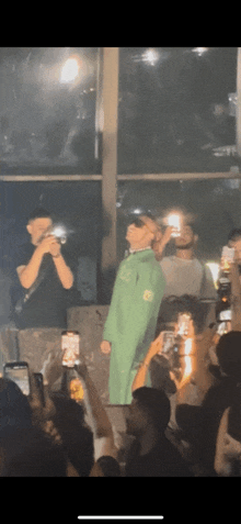 a man in a green suit stands in front of a crowd