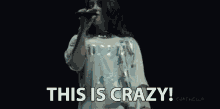 a woman singing into a microphone with the words this is crazy