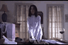 a woman is standing on top of a bed in a bedroom .