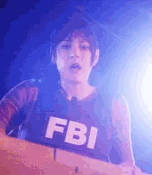 a person wearing a fbi vest stands in front of a blue light