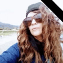 a woman with long hair and sunglasses is taking a selfie .