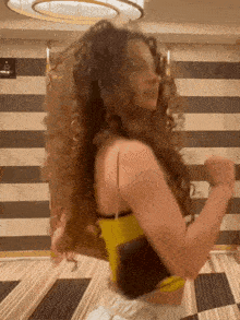 a woman with curly hair is dancing in a room