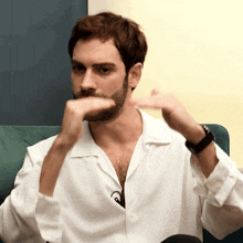a man with a beard wears a white shirt and a watch
