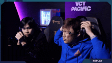 two men are sitting in front of a sign that says vct pacific on it