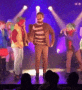 a group of people standing on a stage with purple lights