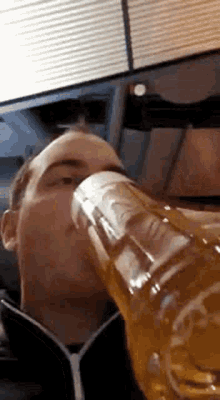 a man is drinking a glass of beer from a bottle .