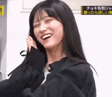a woman with long black hair is smiling and making a face
