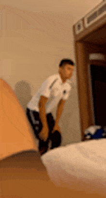 a blurry picture of a man standing next to a bed in a room .
